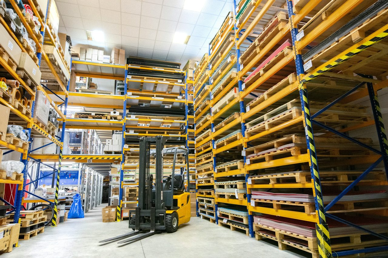 A forklift drives between the racks of a building-materials warehouse